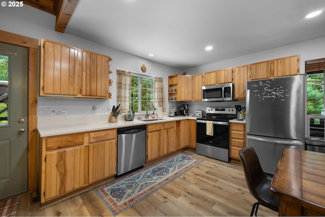 kitchen featuring light wood-style flooring, a sink, light countertops, appliances with stainless steel finishes, and open shelves