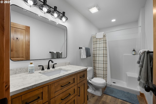 bathroom with toilet, wood finished floors, visible vents, vanity, and a shower stall