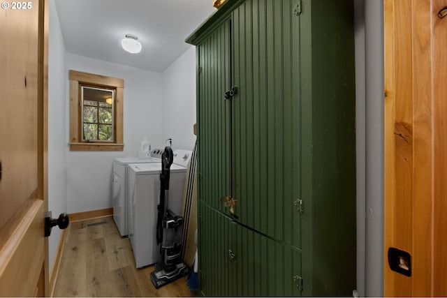 laundry area featuring washer and clothes dryer, light wood-type flooring, and baseboards