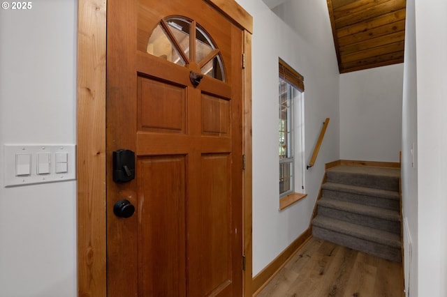 entrance foyer featuring lofted ceiling, stairway, light wood-style flooring, and baseboards