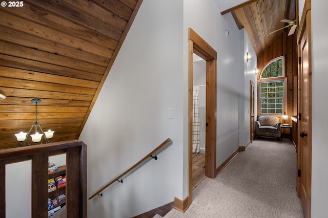 hallway with wooden ceiling, carpet flooring, vaulted ceiling, and an upstairs landing