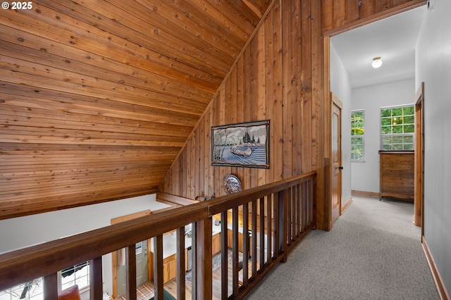 corridor featuring carpet, wood ceiling, vaulted ceiling, wood walls, and baseboards