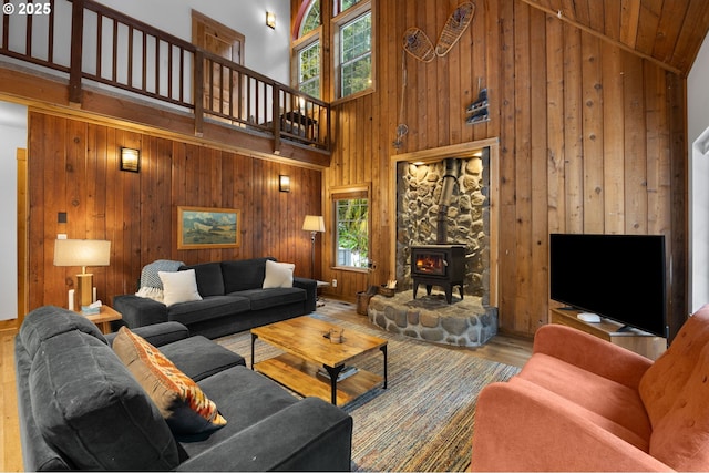 living area with a wood stove, wood walls, high vaulted ceiling, and wood finished floors