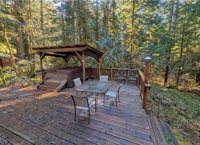 wooden terrace featuring a forest view and a hot tub