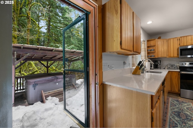 kitchen featuring appliances with stainless steel finishes, brown cabinets, light countertops, open shelves, and a sink