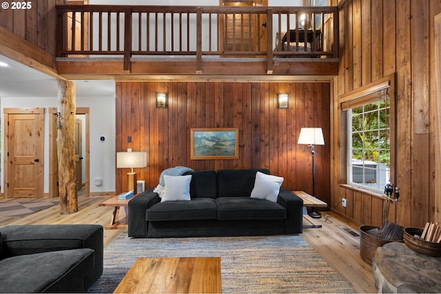 living room featuring wood walls, a high ceiling, and wood finished floors