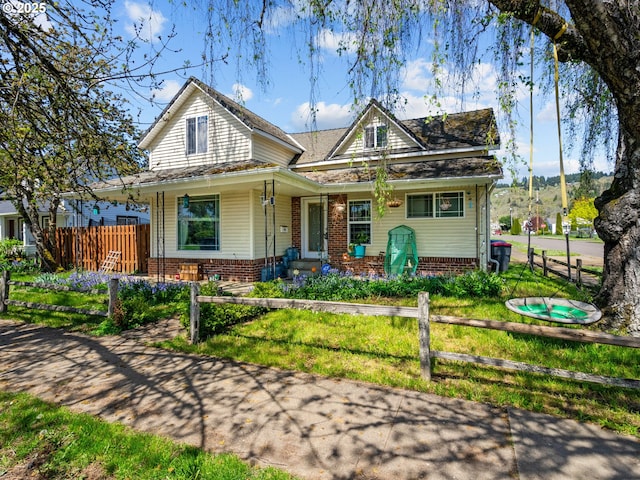 view of front facade featuring brick siding, a front lawn, and a fenced front yard