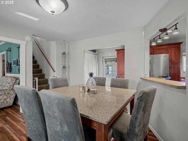dining space featuring dark wood-type flooring and stairs