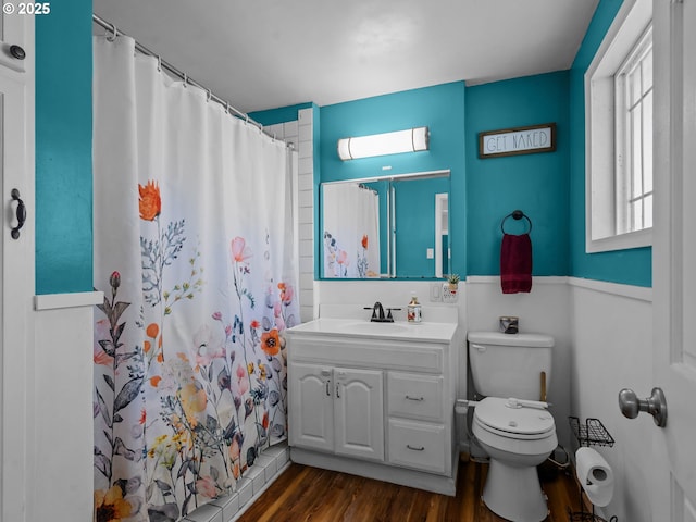 full bath with toilet, wood finished floors, vanity, and a healthy amount of sunlight