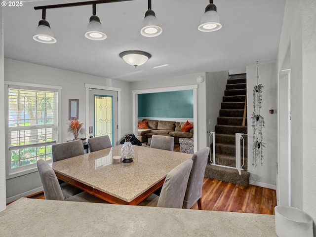 dining area with baseboards, wood finished floors, and stairway