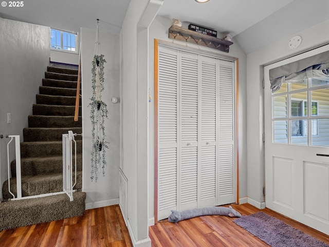 foyer entrance with stairs, lofted ceiling, wood finished floors, and baseboards