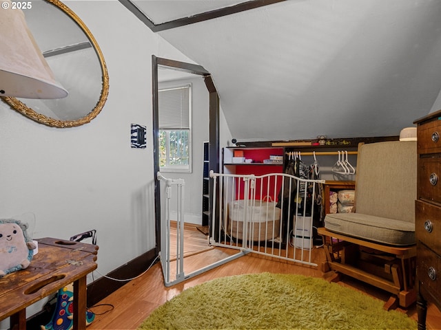 bedroom featuring lofted ceiling, baseboards, and wood finished floors