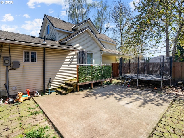 back of house featuring fence, a patio area, a deck, and a trampoline