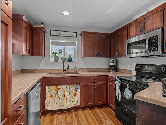 kitchen featuring light wood-type flooring, stainless steel appliances, light countertops, and a sink