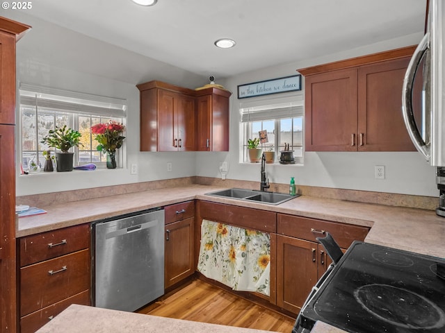 kitchen with light countertops, electric range oven, stainless steel dishwasher, and a sink
