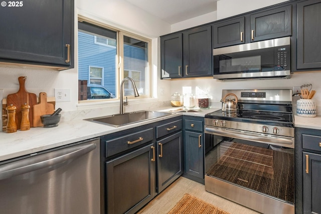 kitchen featuring light stone countertops, appliances with stainless steel finishes, and a sink