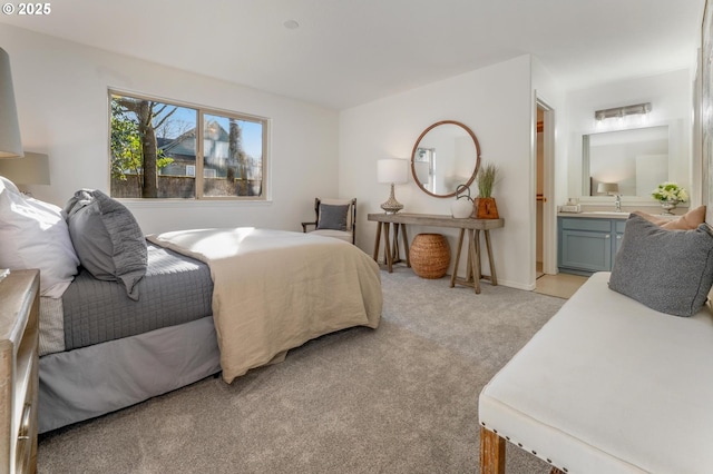 bedroom with light carpet, a sink, and ensuite bathroom