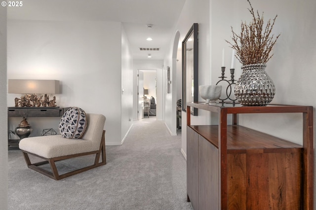 hall featuring carpet floors, visible vents, baseboards, and arched walkways