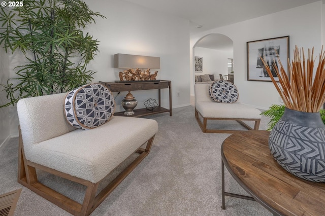 sitting room with carpet, visible vents, arched walkways, and baseboards