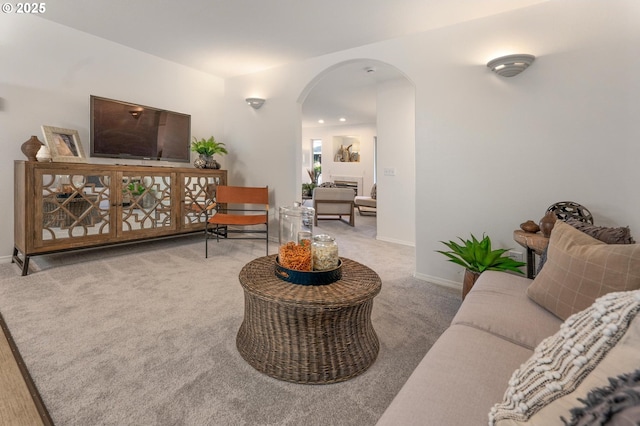 living room with arched walkways, carpet flooring, and baseboards