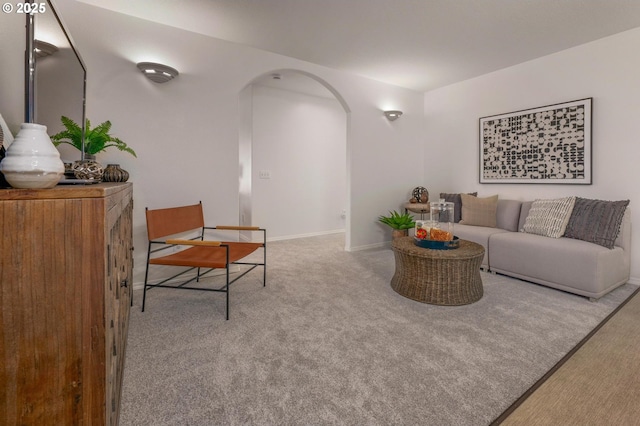 living area featuring arched walkways, carpet floors, and baseboards