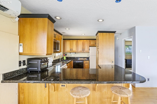 kitchen featuring a kitchen breakfast bar, kitchen peninsula, an AC wall unit, and electric range oven