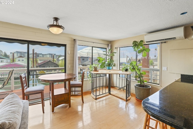 dining space featuring light hardwood / wood-style floors, a textured ceiling, and a wall unit AC