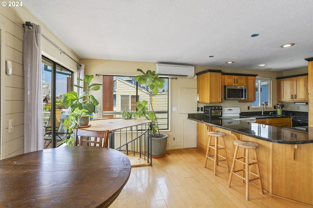 kitchen featuring kitchen peninsula, light wood-type flooring, white range with electric stovetop, a wall mounted AC, and sink