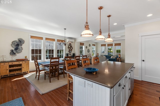kitchen featuring dark countertops, crown molding, dark wood-style floors, a kitchen island, and a wall mounted AC