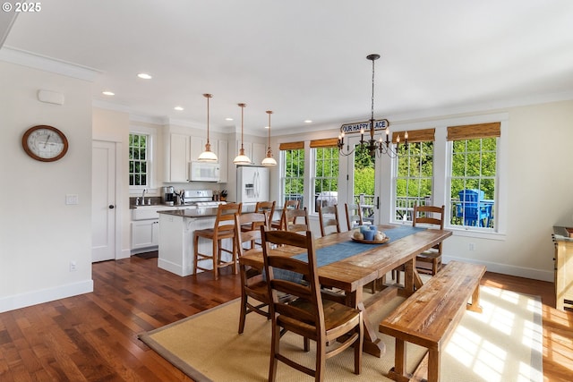 dining room with a chandelier, crown molding, baseboards, dark wood finished floors, and recessed lighting