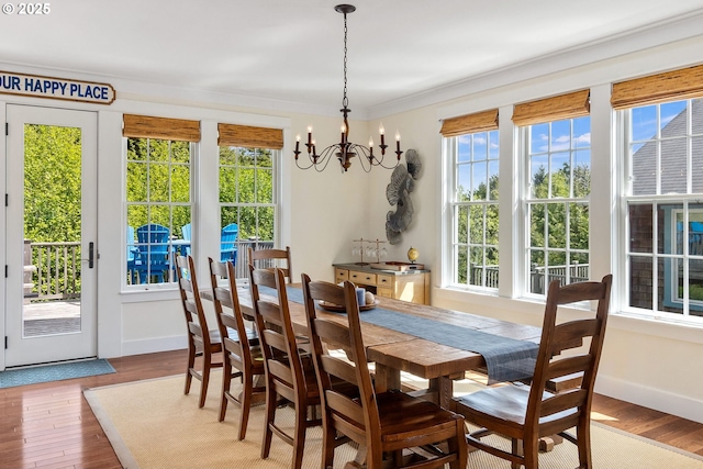 dining area with plenty of natural light, a chandelier, wood finished floors, baseboards, and crown molding