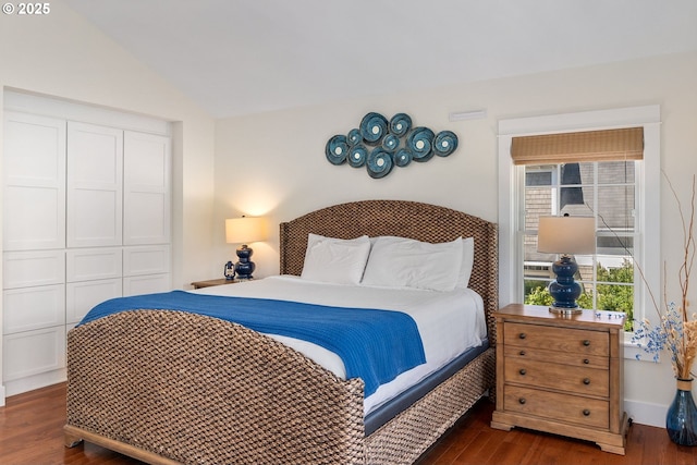 bedroom featuring dark wood-style flooring, a closet, and vaulted ceiling