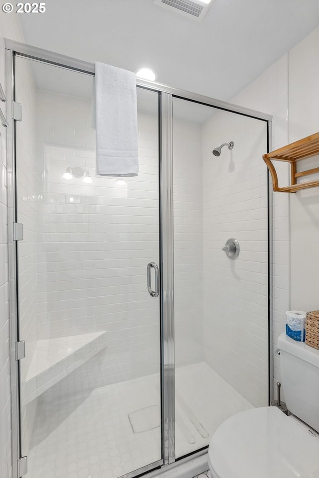 bathroom featuring toilet and a stall shower