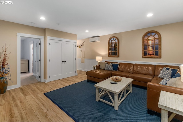 living room featuring a wall mounted air conditioner, light wood-style flooring, recessed lighting, and baseboards