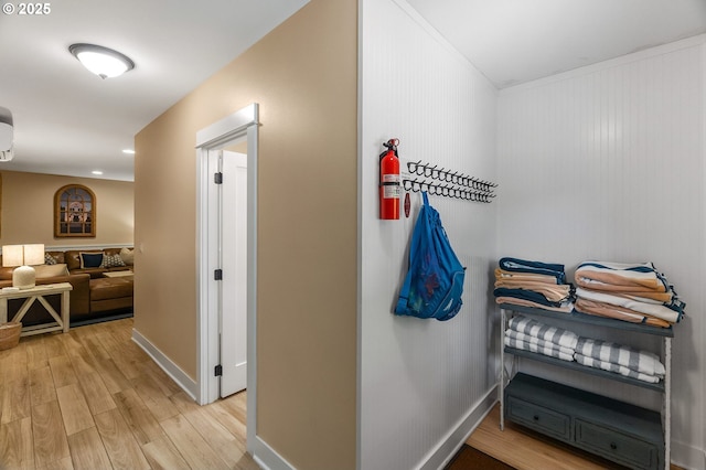 hallway featuring light wood-type flooring, baseboards, and ornamental molding