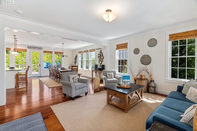 living area with wood finished floors, crown molding, baseboards, an AC wall unit, and french doors