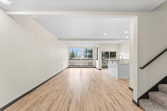 unfurnished living room featuring sink and light hardwood / wood-style floors