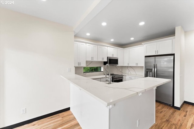 kitchen with light stone countertops, stainless steel appliances, kitchen peninsula, white cabinets, and light wood-type flooring