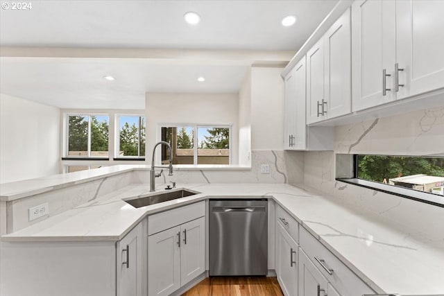 kitchen featuring dishwasher, light stone counters, white cabinetry, and sink