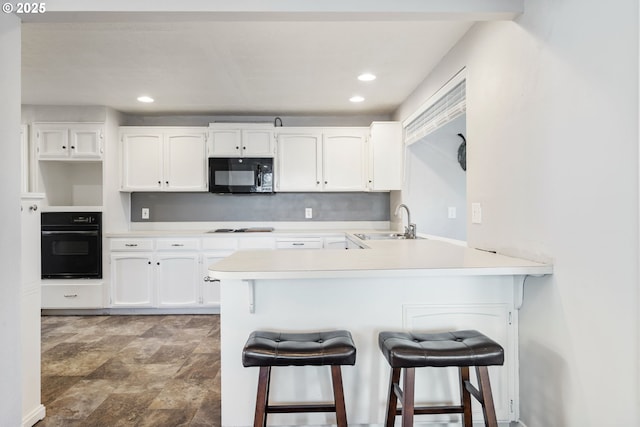 461 NE 16th Ave, Hillsboro, OR 97124 - kitchen with black appliances, a sink, white cabinets, a breakfast bar, and recessed lighting
