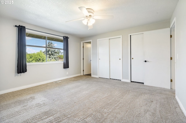 461 NE 16th Ave, Hillsboro, OR 97124 - unfurnished bedroom with multiple closets, carpet, baseboards, a textured ceiling, and ceiling fan