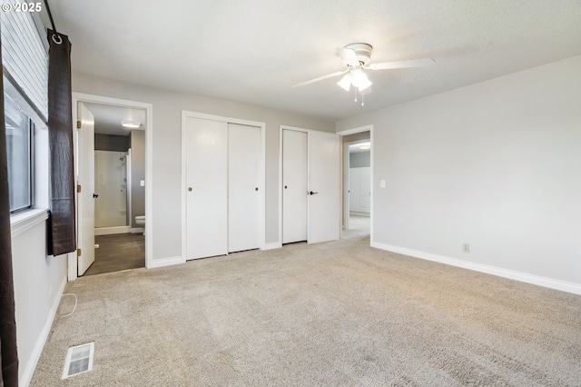 461 NE 16th Ave, Hillsboro, OR 97124 - unfurnished bedroom featuring two closets, carpet floors, ensuite bathroom, baseboards, and a ceiling fan