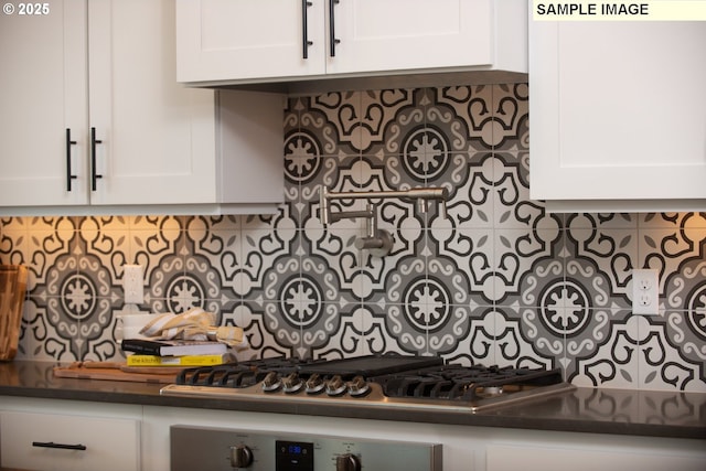 kitchen with dark countertops, stainless steel gas stovetop, white cabinetry, and decorative backsplash