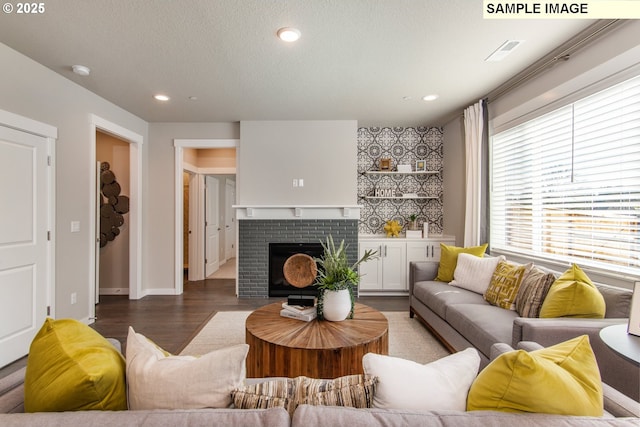 living area with visible vents, light wood-style flooring, a textured ceiling, a brick fireplace, and recessed lighting