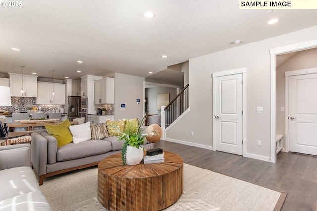 living area featuring baseboards, stairway, wood finished floors, and recessed lighting