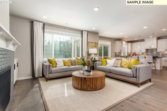 living room with a brick fireplace, wood finished floors, and recessed lighting