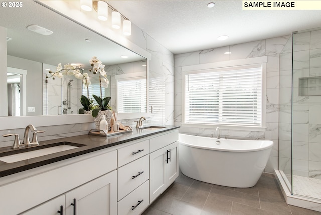 full bathroom with a stall shower, a sink, tile walls, and a textured ceiling