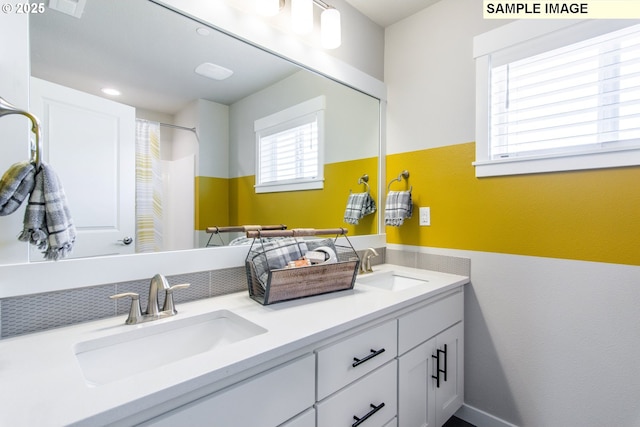 bathroom with curtained shower, a sink, and double vanity