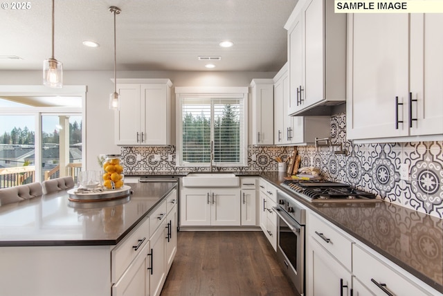 kitchen with dark countertops, white cabinetry, stainless steel appliances, and a sink