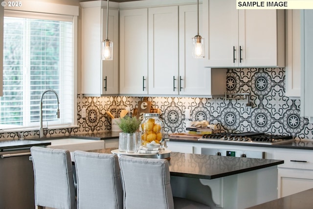 kitchen featuring tasteful backsplash, dark countertops, white cabinets, and stainless steel gas stovetop